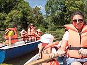 Familie mit Kindern, mit Rettungswesten ausgestattet, beim Bootfahren.