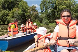 Familie mit Kindern, mit Rettungswesten ausgestattet, beim Bootfahren.