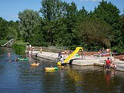 Badende im Wörnitz-Flussfreibad in Oettingen. Auf dem Bild ist auch die Rutsche für die Kinder zu sehen.