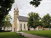 Blick auf die Pfarrkirche St. Sebastian, die teilweise hinter Bäumen verborgen ist.