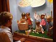 Ein Junge betrachtet eine Puppenszene im Käthe Kruse Puppenmuseum.