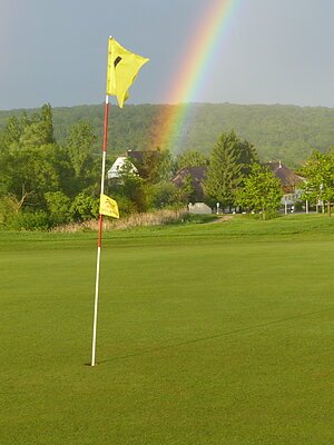 Golfplatz Donauwörth Markierung / Fahne auf dem Rasen vom Golfplatz - im Hintergrund ein Regenbogen am Himmel .