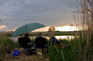 Drei Angler sitzen am Ufer der Wörnitz bei Oettingen und angeln