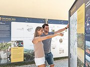 Ein Mann und eine Frau betrachten eine Informationstafel über den Geopark Ries.